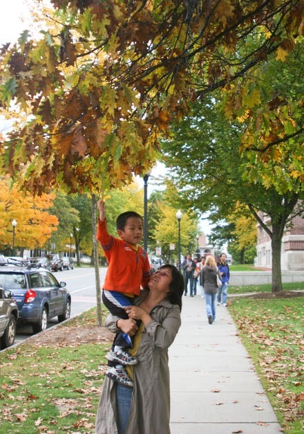 A tourist and her young child visiting the College admire the changing leaves on Wednesday, outside of Baker Library.