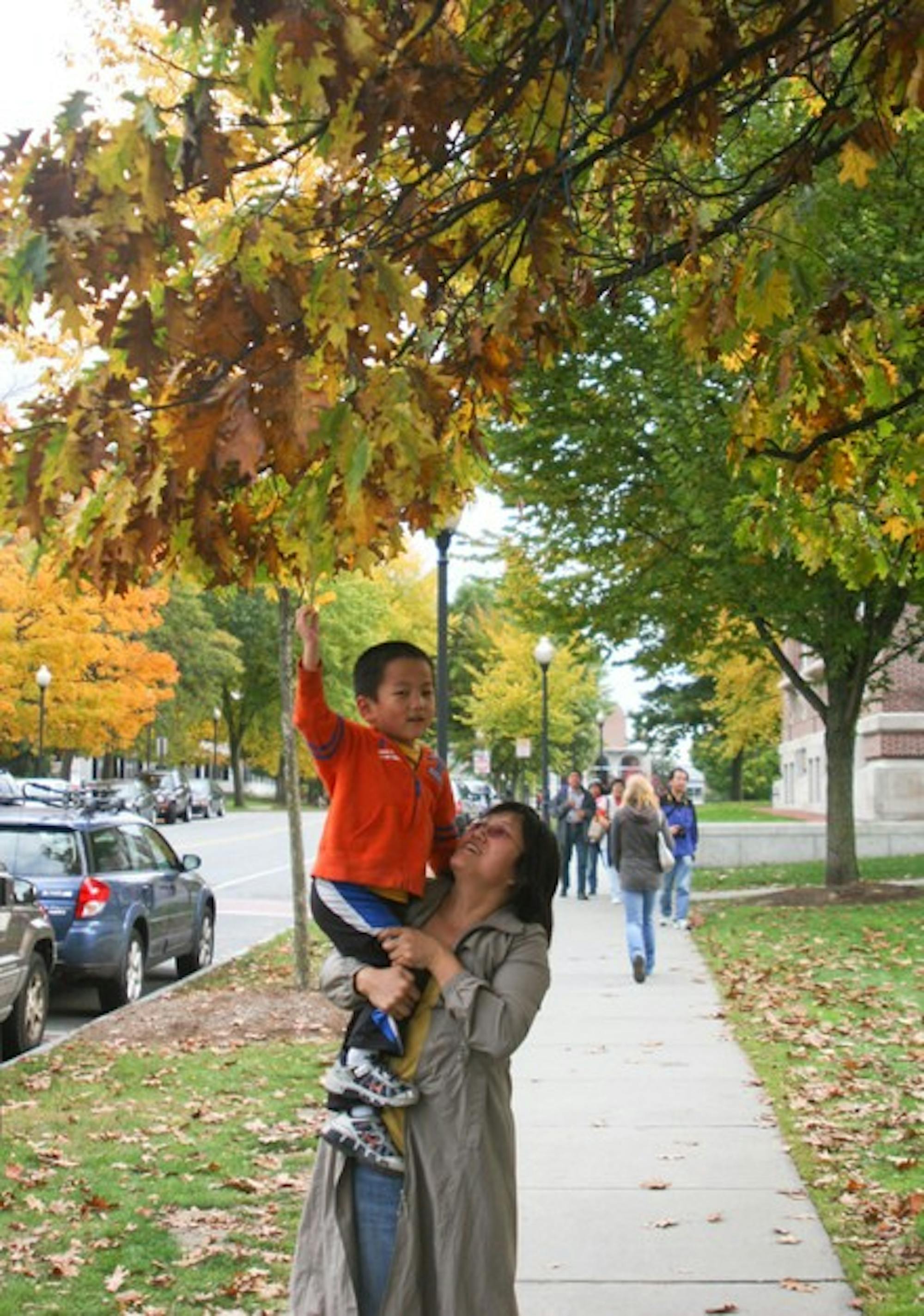 A tourist and her young child visiting the College admire the changing leaves on Wednesday, outside of Baker Library.