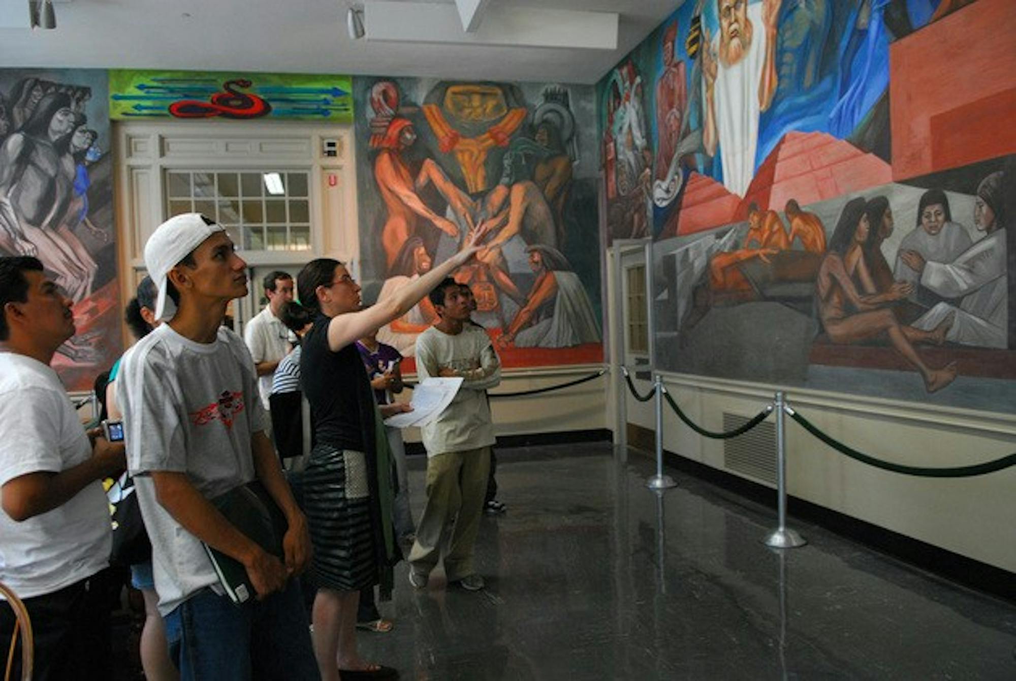 Nicaraguan students participating in the cross-cultural exchange admire the Orozco murals in the reserve corridor of Baker library.