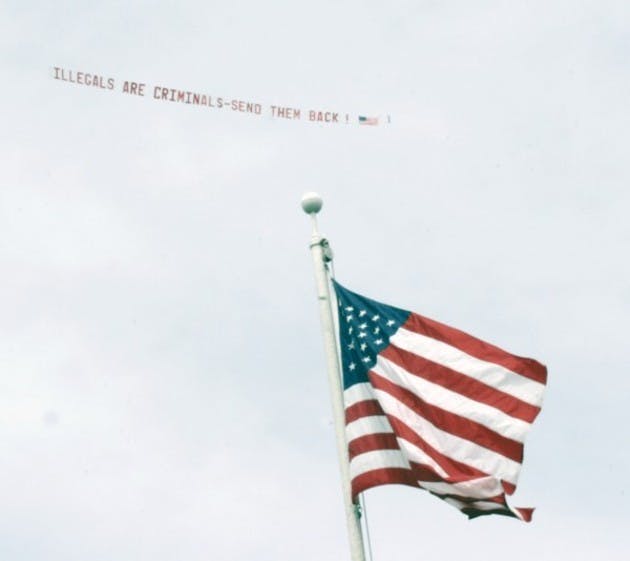 A plane, hired by The Dartmouth Review, tows a banner calling illegal immigrants criminals; the plane circled the Green during the protest Monday afternoon.