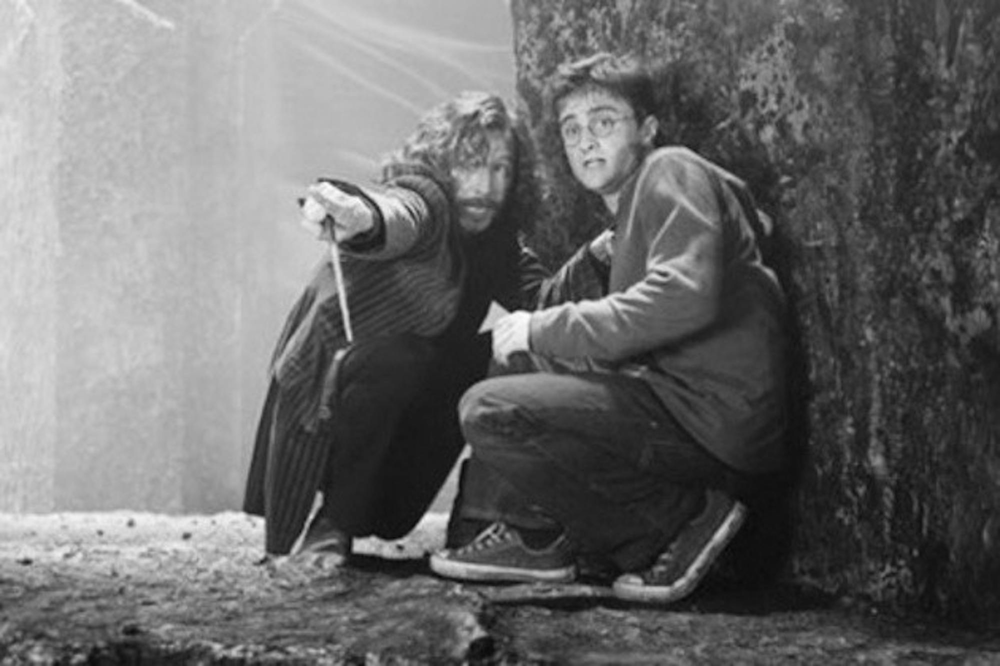 Harry Potter (Daniel Radcliffe) crouches in fear with Sirius Black (Gary Oldman). The fifth movie marks a darker turn in Harry's life.
