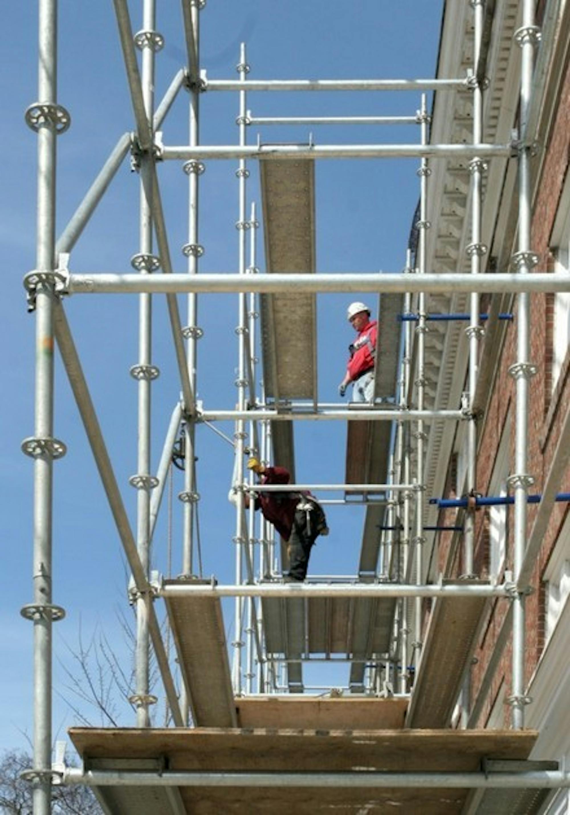 Workers scale scaffolding Wednesday at the Hanover Inn, where projects are underway to fix the roof, copper the dormers and make general repairs.