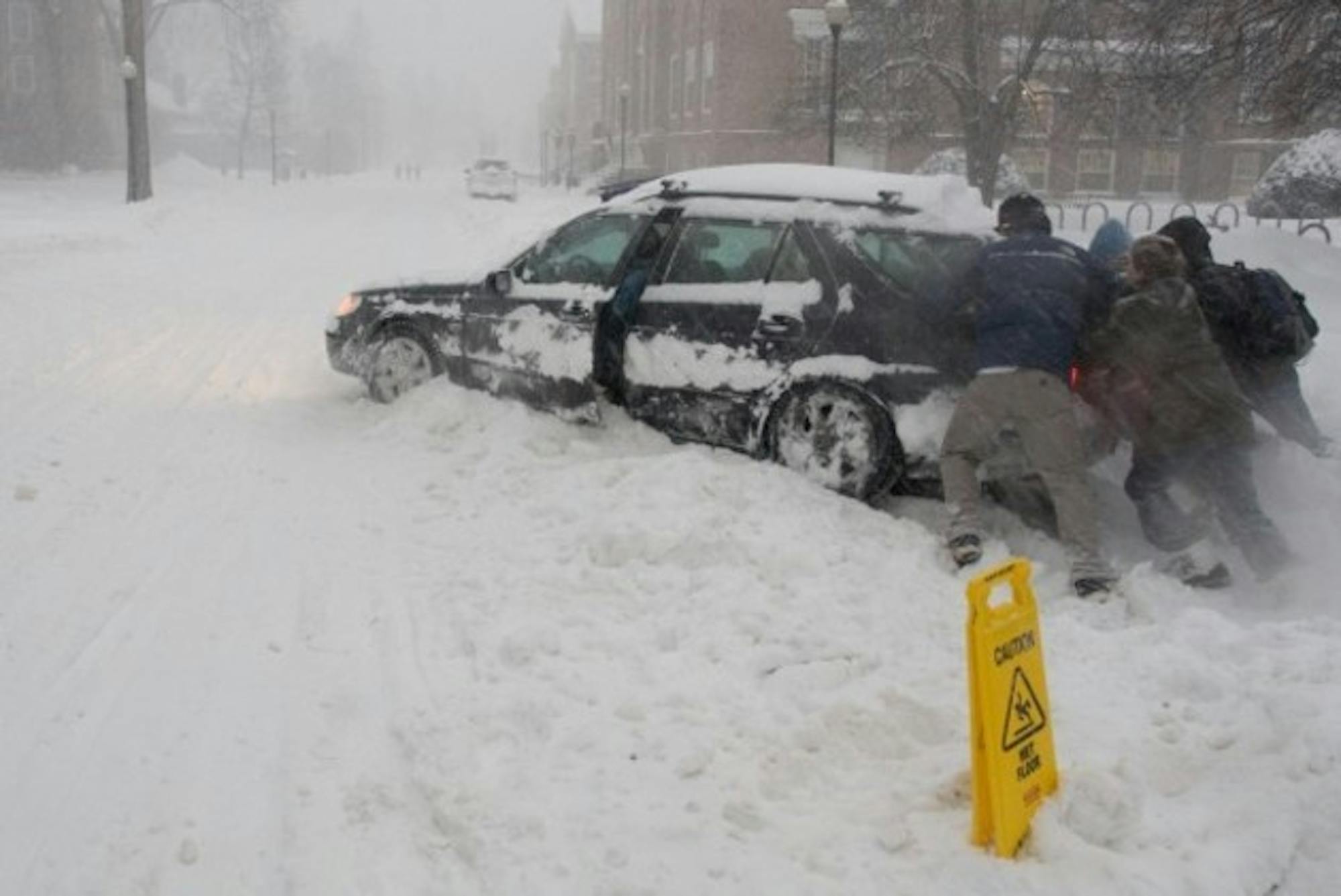 A few undergraduates help a MALS student extract her car from the snowbank. It snowed over a foot Wednesday.
