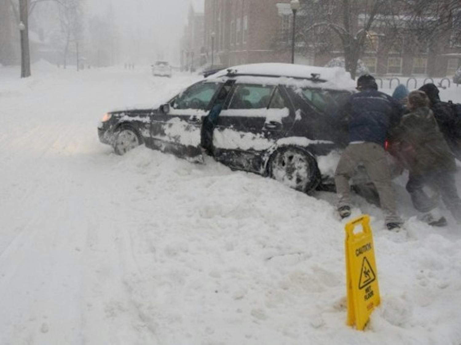 A few undergraduates help a MALS student extract her car from the snowbank. It snowed over a foot Wednesday.
