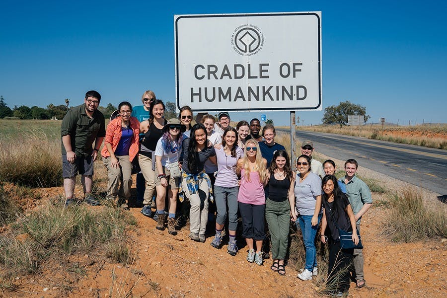 The class poses at the entrance to the Cradle of Humankind World Heritage Site, a region famous for the many hominid species discovered there. During their week at the Cradle of Humankind, the students visited several archaeological sites and worked on a dig.Front row: Adam Nemeroff, an instructional designer who traveled with the class; Jessica Kittleberger ’18; Kathy Li ’17; Keira Byno ’19; Elizabeth T. K. (Kalei) Akau ’18; Katherine Clayton ’18; Lauren Gruffi ’17; Olivia Wiener ’19; Cindy Ramirez ’18; Saemi Han ’18. Back row: Ellison McNutt GR; Jacqueline Saralegui ‘18; Julia Cohen ‘18; Jeremy DeSilva, one of the professors leading the class; Sarah Miller ‘19; Eric (??? Driver); Abigail Reynolds ‘17; Nathaniel Dominy, a professor who led the class with DeSilva; Erica Ng ’19; Michael Everett ‘19., South Africa, Anthropology 70