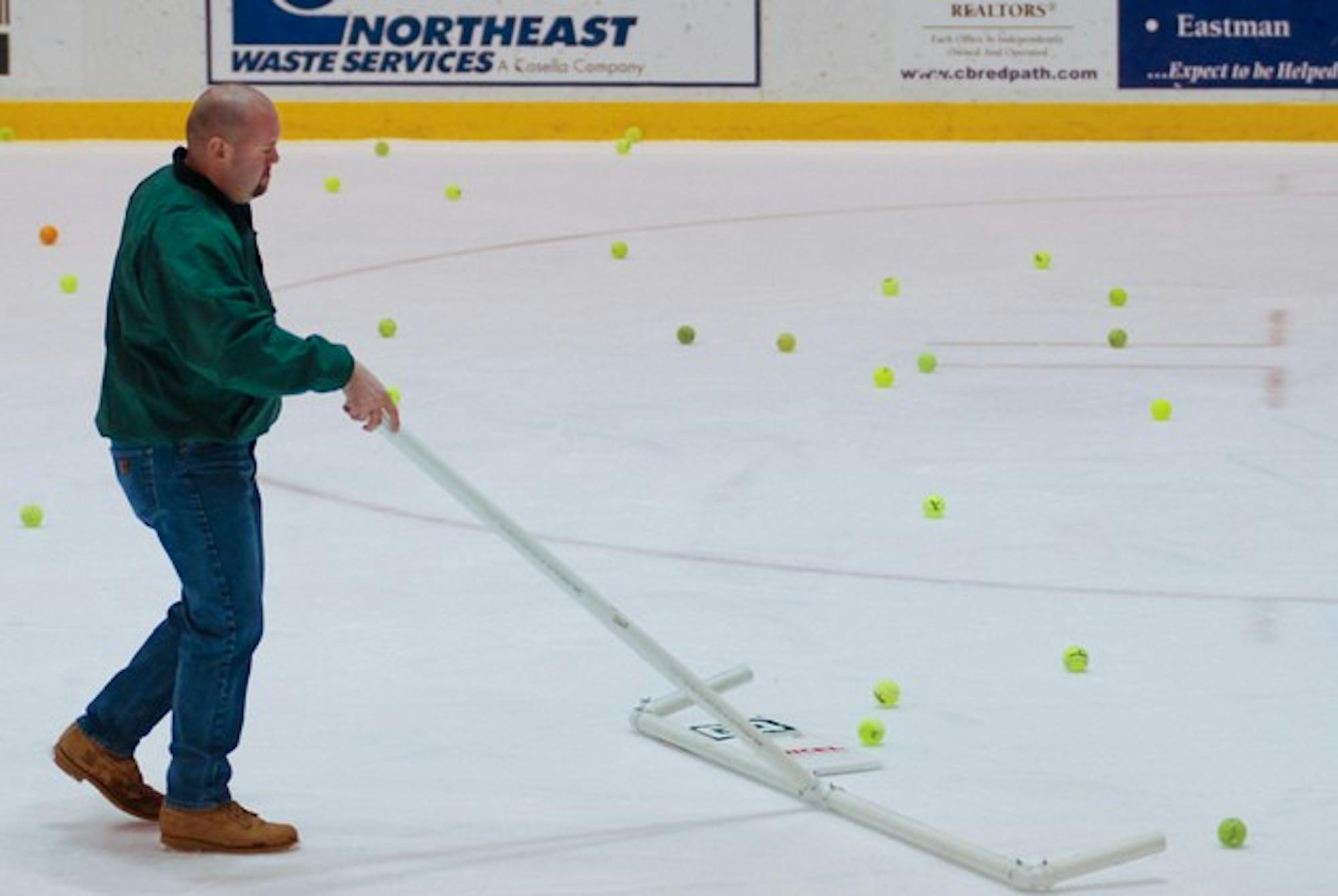 A Thompson Arena staff member cleans up tennis balls thrown onto the ice after the Big Green scored its first goal during last year's Princeton game.