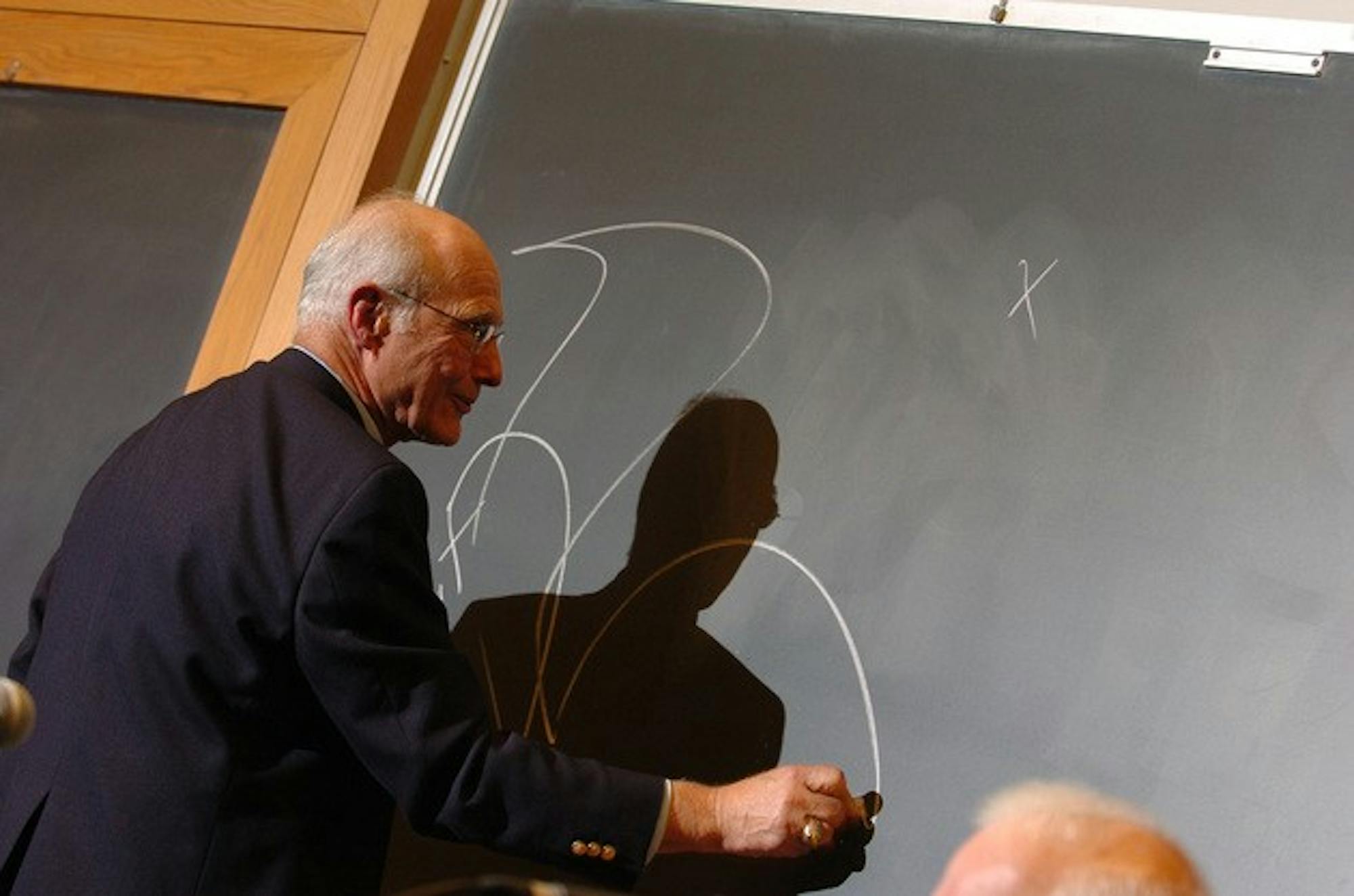 Dartmouth-Hitchcock Medical Center pediatrician Alan Rozycki '61 illustrates his point on a Rockefeller Center blackboard during his discussion of ethics at a panel sponsored by Undergraduate Judicial Affairs.