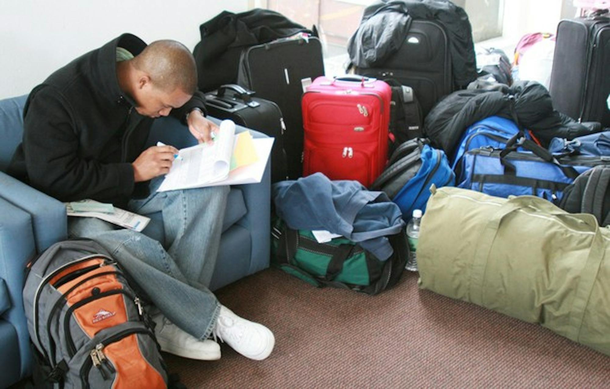 Prospective student Kadian Campbell reviews his events schedule for this week's Dimensions activities amid a forest of prospie luggage.