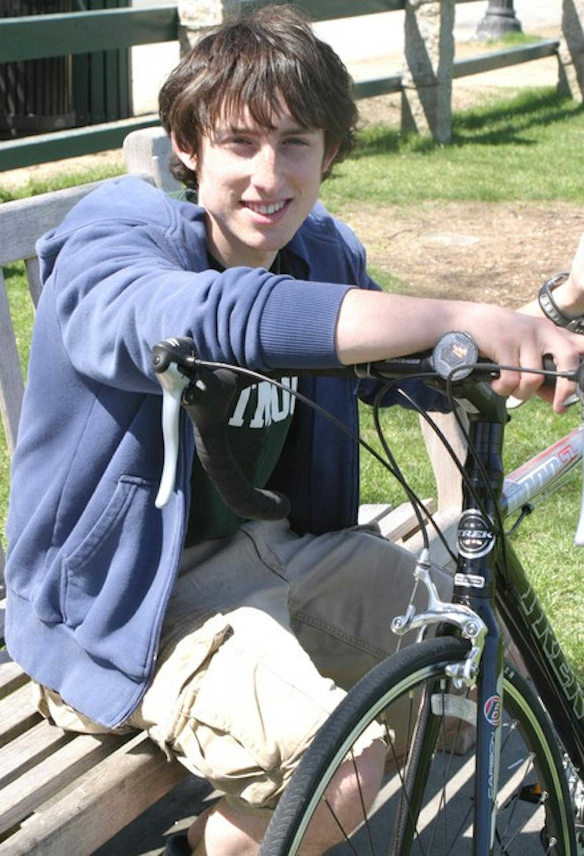 Bike and Build participant Billy Corbett '10 sits with his bike on the Green.
