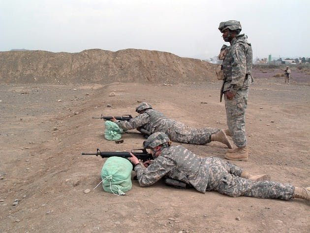 1st Lt. Liz Hunt '05, the soldier lying in the front of the foreground above, practices at a range with two fellow soldiers serving in Afghanistan.