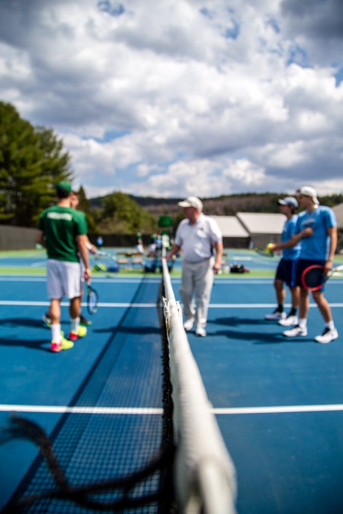 The tennis coach speaks to players during a cloudy day's practice.