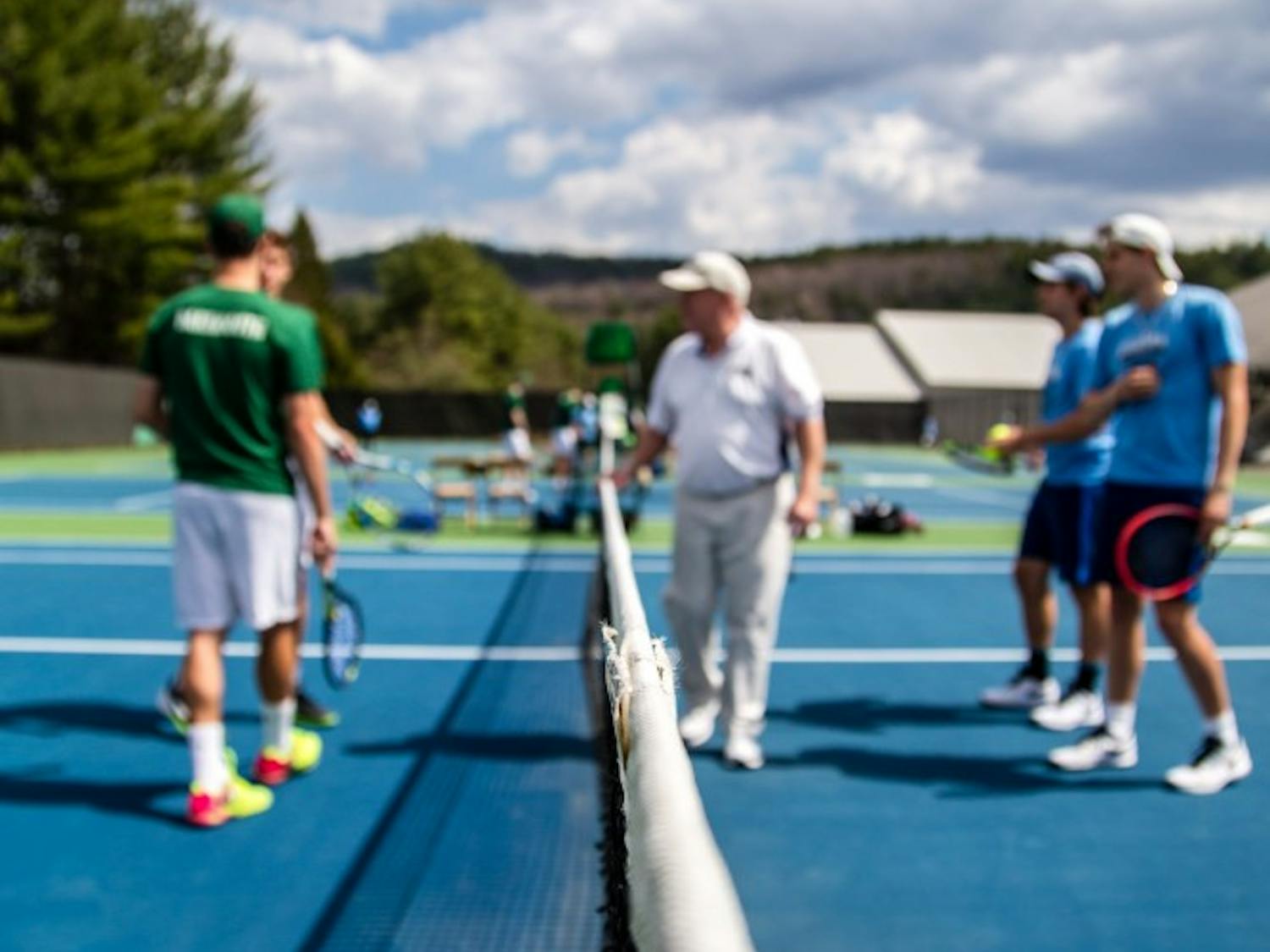 The tennis coach speaks to players during a cloudy day's practice.