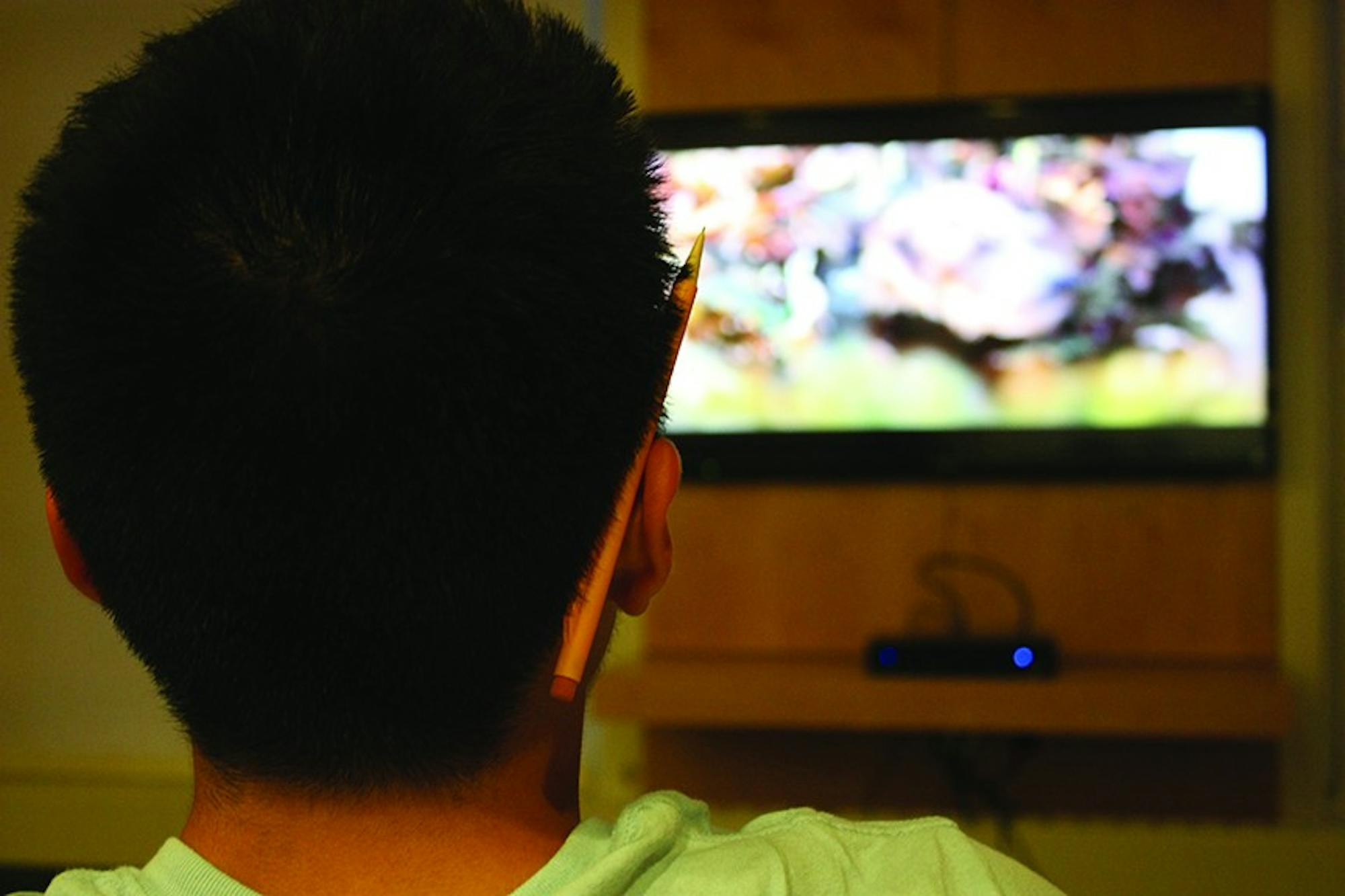 A student takes in a television show at the Collis Center.