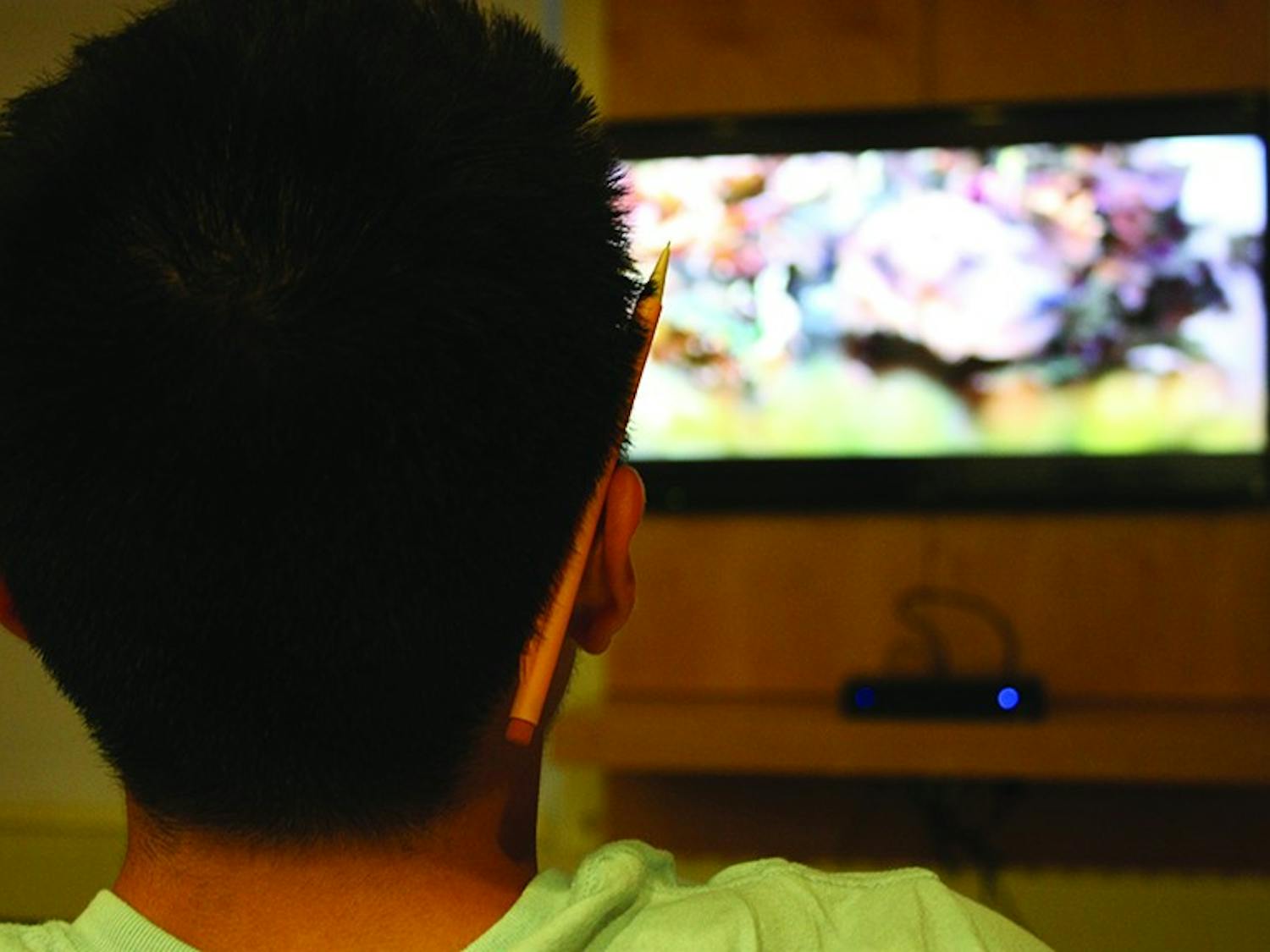 A student takes in a television show at the Collis Center.