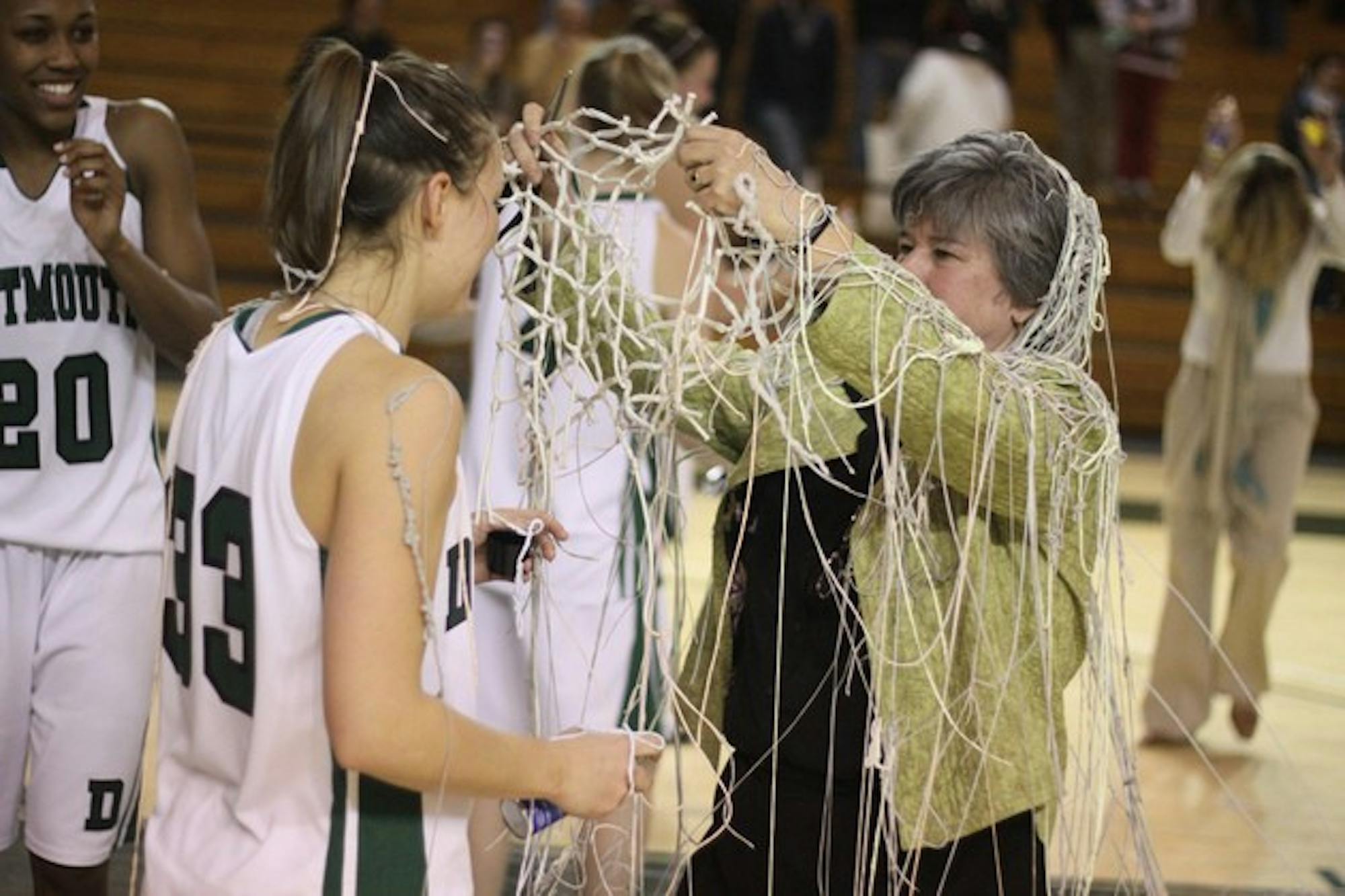 Silly-string-covered head coach Chris Wielgus presents Koren Schram '09 with the net during the postgame celebration after the women's basketball team won its 17th Ivy League championship.