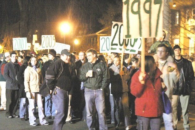 Following current students, alumni from recently graduated classes process around the Green during Homecoming.