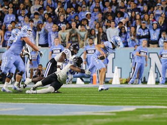 Redshirt sophomore defensive tackle Aaron Hall reaches for North Carolina quarterback Drake Maye's legs in the teams' Saturday night clash.
