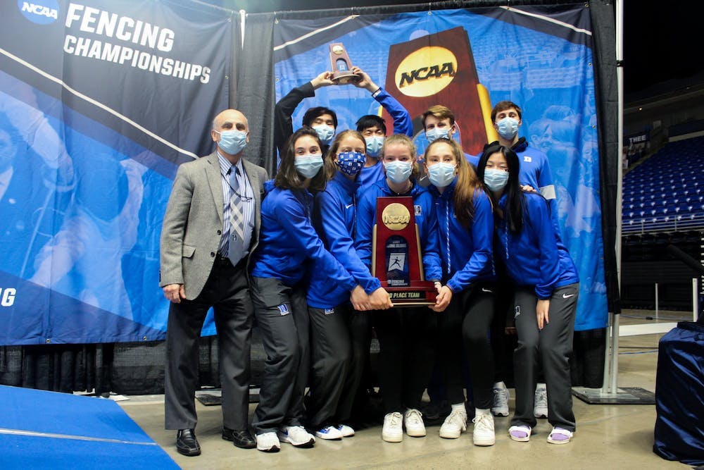<p>Head coach Alex Beguinet (left) poses with his team after finishing third in the 2021 NCAA Championships.</p>