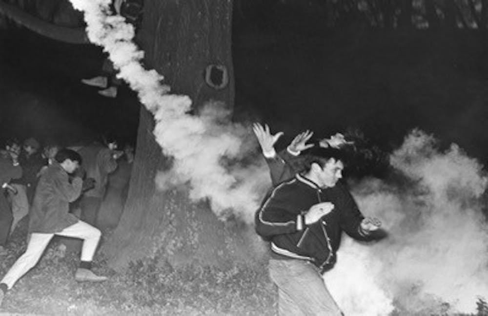 Tear gas scatters the onlookers and supporters outside of Allen Building. Courtesy of Durham Civil Rights Heritage Project (The Herald Sun).
