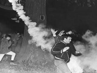 Tear gas scatters the onlookers and supporters outside of Allen Building. Courtesy of Durham Civil Rights Heritage Project (The Herald Sun).
