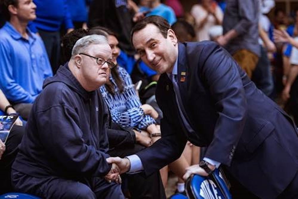 Coach K shakes hands with Steve Mitchell, who sat directly behind the Duke bench for every home game from the 1980-81 season until his death in 2017.