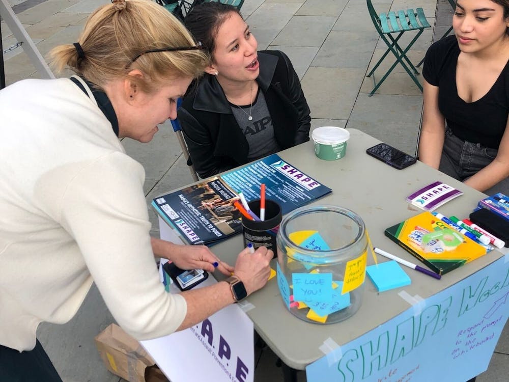 Mary Pat McMahon, vice provost/vice president for student affairs, at a SHAPE week table with two students.