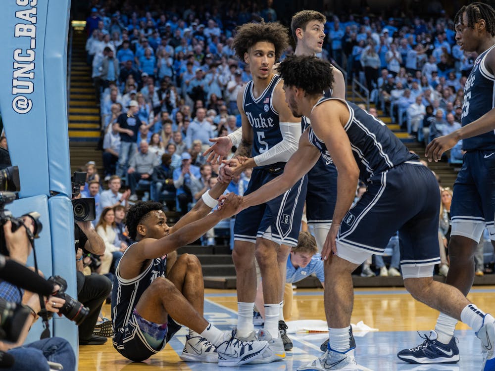 Tyrese Proctor (middle) and Jared McCain (right) help Jeremy Roach (left) to his feet during the first half of Duke's loss to North Carolina.