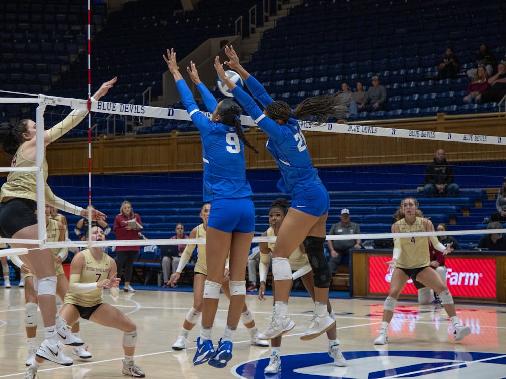 Two Duke players, Taylor Williams (9) and Ariana White (21), leap for a block against Florida State.