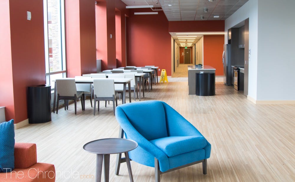A sweeping hall space with tables and a kitchen area greet students inside. 