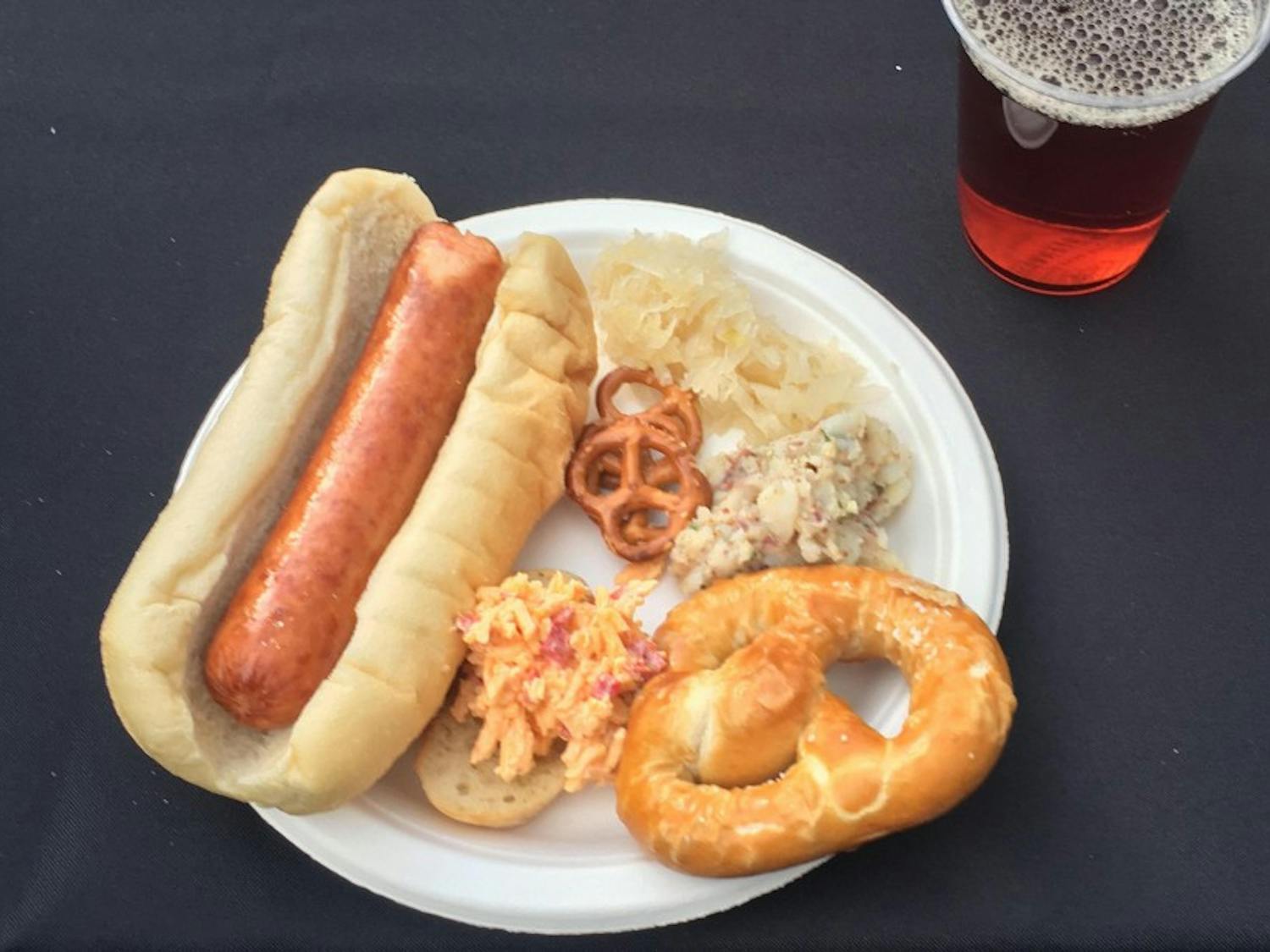 A plate with Polish sausage, sauerkraut, Obazda and pretzels.
