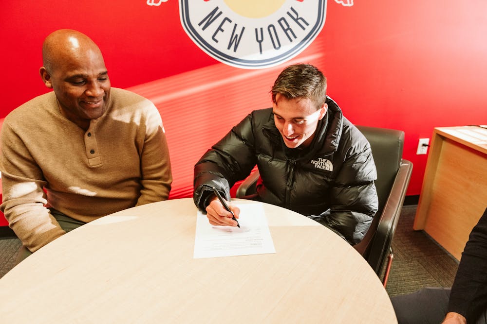 Peter Stroud signs his contract alongside New York Red Bulls sporting director Denis Hamlett.