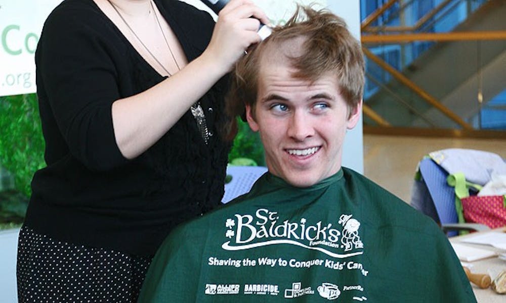 Volunteer stylist Amy Torres shaves the head of a member of the Duke Rugby club team to support childhood cancer research.