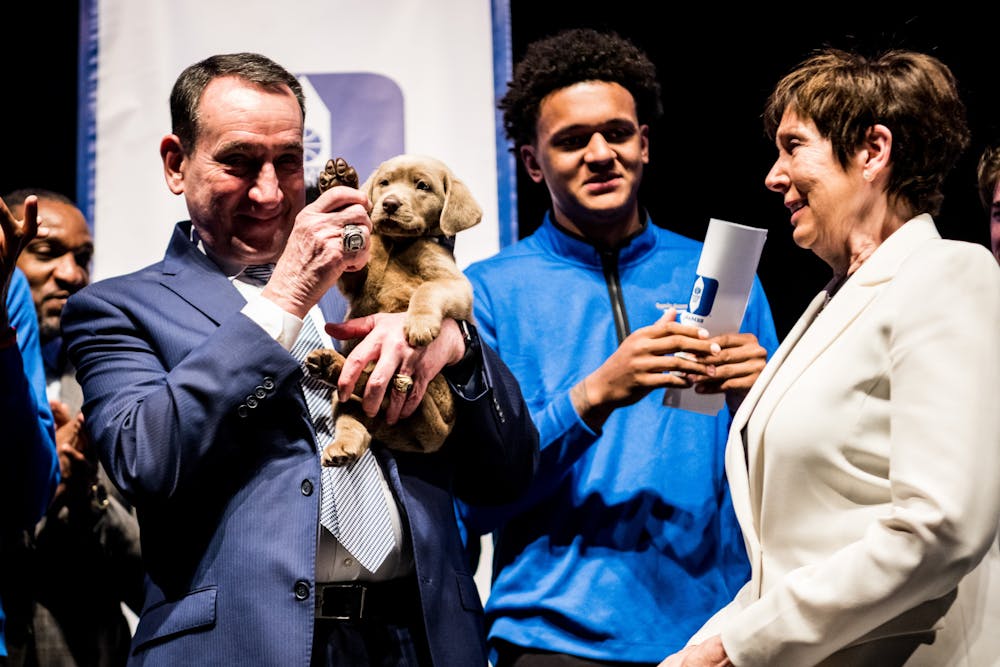 Former head coach Mike Krzyzewski holds Coach on stage at the team's annual awards banquet.