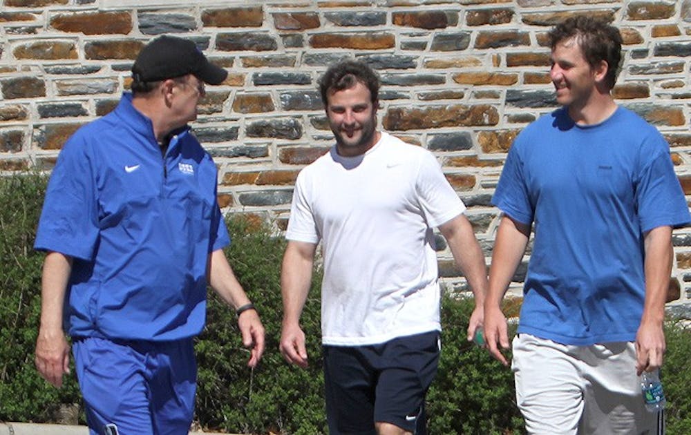 NFL stars Eli Manning and Wes Welker walk with Duke head coach David Cutcliffe outside the Yoh Football Center. Peyton Manning was close behind.