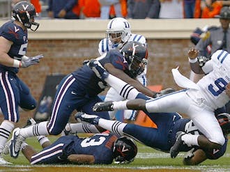 Quarterback Thaddeus Lewis is tackled on a running play during the Blue Devils’ 28-17 ACC victory over Virginia Saturday at Scott Stadium in Charlottesville, Va.