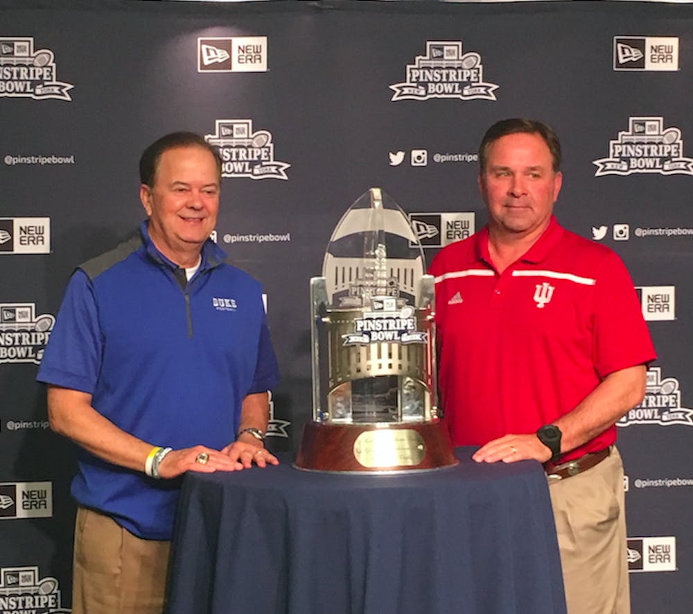 <p>Duke head coach David Cutcliffe and Indiana head coach Kevin Wilson pose with the Pinstripe Bowl trophy Friday.</p>