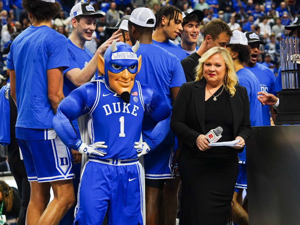 The Blue Devil poses next to the ACC tournament trophy following Duke's win.