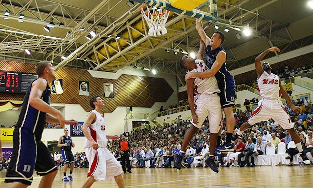 Miles Plumlee goes up for a dunk over Qais Omar in Duke’s final exhibition game in Dubai while his brother Mason looks on.