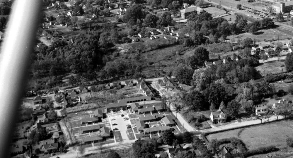 <p>Erwin Mills is at the top right of this 1950s era aerial photograph of the area that became Central Campus. The land at the bottom right is now the 300 Swift Apartments and the land at the back of the shot is now Central Campus. Photo via Open Durham and Durham Herald-Sun.</p>