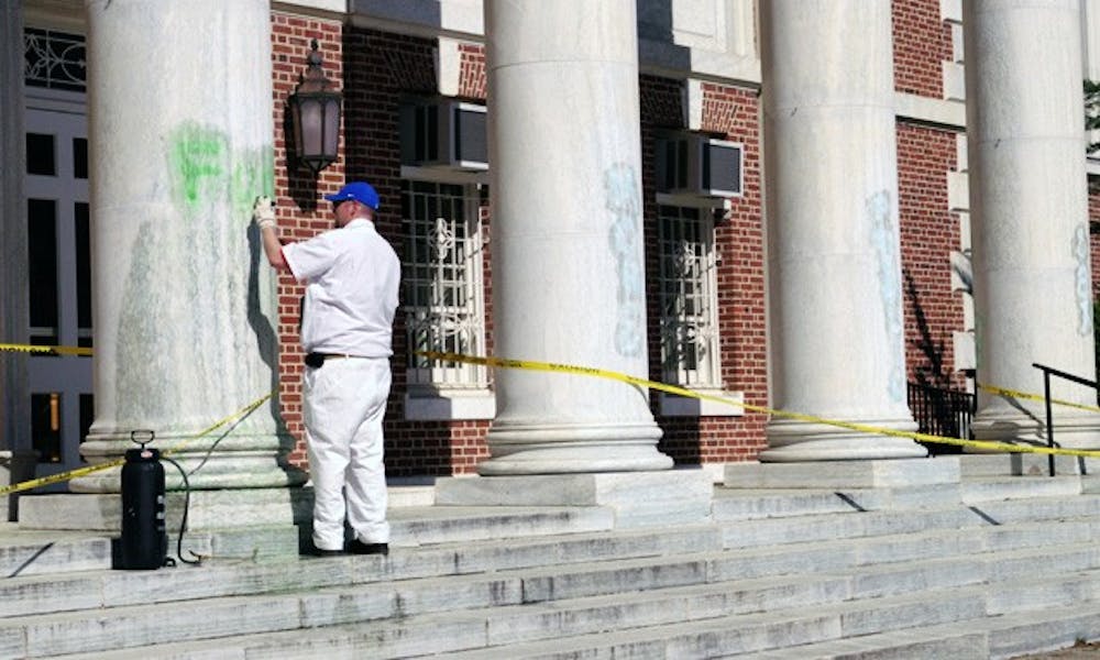 A University staff member cleans up graffiti painted Saturday on the columns of Lilly Library on East Campus. Wilson Residence Hall was similarly vandalized.