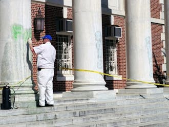 A University staff member cleans up graffiti painted Saturday on the columns of Lilly Library on East Campus. Wilson Residence Hall was similarly vandalized.