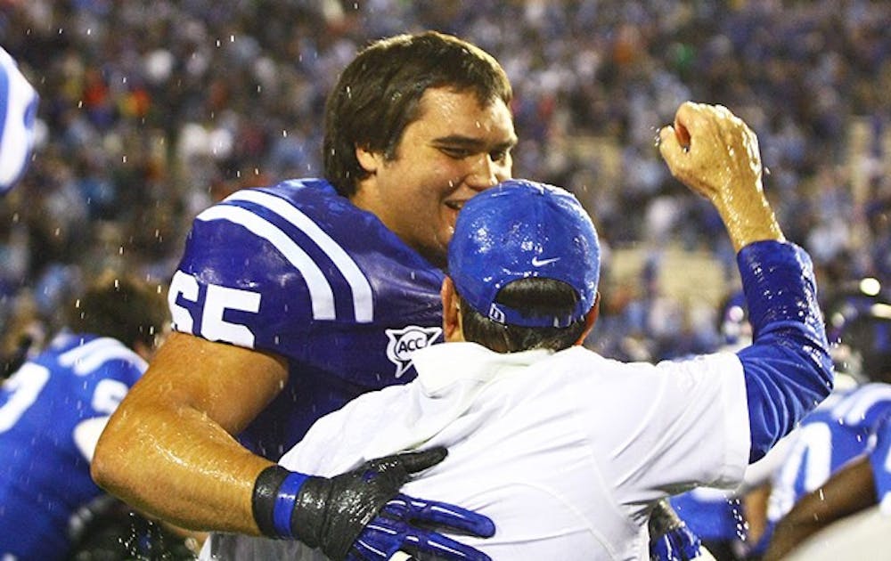 Cutcliffe, pictured here with Cody Robinson, a senior on the 2012 roster, had a 14-season tenure which included a stretch of six bowl games in seven years, including the 2012 Belk Bowl, the program's first since 1995. 
