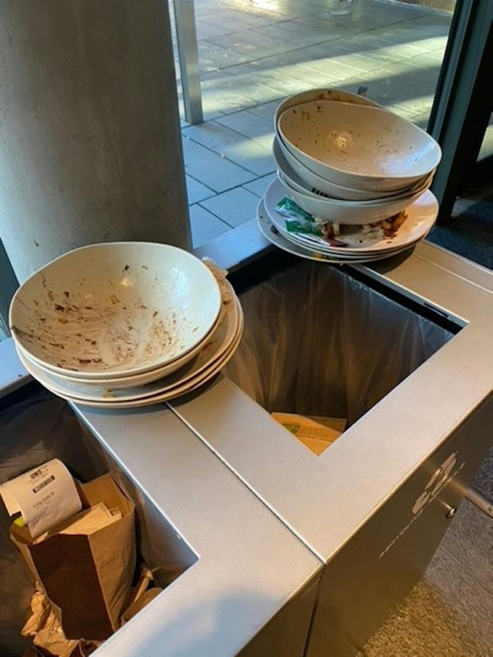 Dirty dishes left by Panera's trashcans