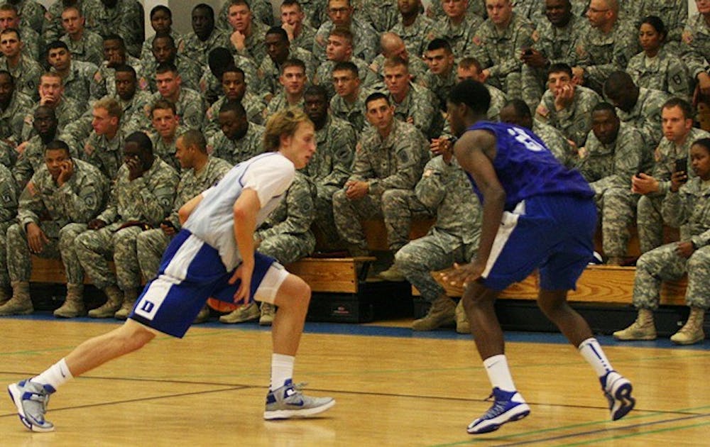 Alex Murphy, left, and Amile Jefferson, right, run drills in front of the troops at Fort Bragg Saturday.