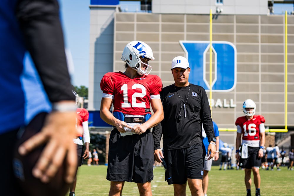 Offensive coordinator Jonathan Brewer speaks with sophomore quarterback Grayson Loftis.