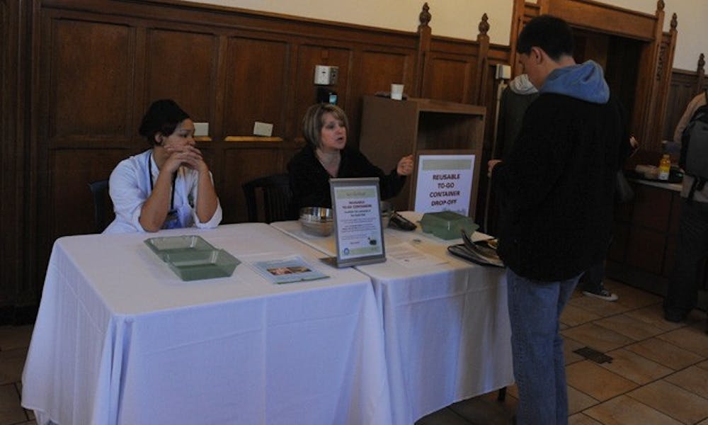 A student learns about the new reusable clamshell containers in The Great Hall. The initiative, which gives students an environmentally friendly container for $5, was proposed by an environmental sciences class.