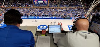 David Shumate (left) checks his notes in the broadcast booth during Duke's home game against Clemson.