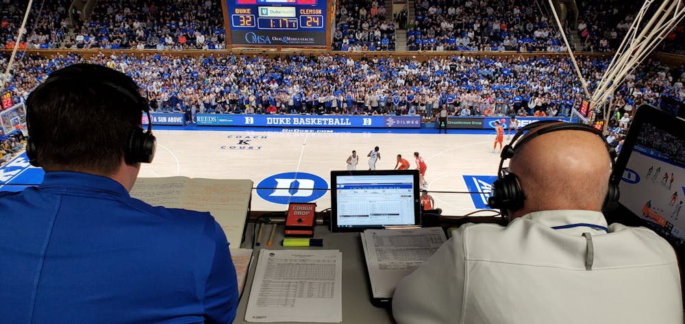 <p>David Shumate (left) checks his notes in the broadcast booth during Duke's home game against Clemson.</p>
