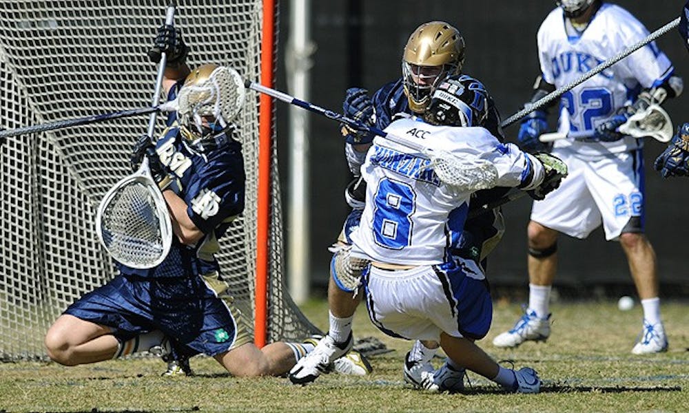 Notre Dame goalie Scott Rodgers goes down to block a shot while Duke attackman Max Quinzani gets hit by a Fighting Irish defenseman Saturday.
