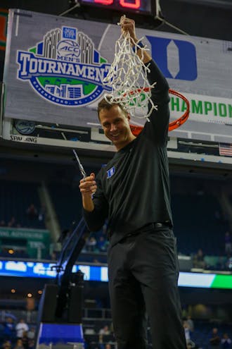 Head coach Jon Scheyer cuts down the net at Greensboro Coliseum following the Blue Devils' ACC title win.